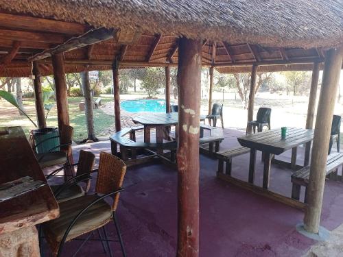 a pavilion with tables and chairs and a pool at Thekwane Holiday House in Klipdrift