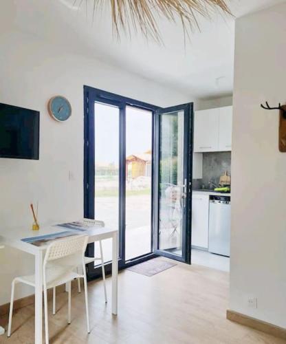 une cuisine avec une table et des chaises et une cuisine avec des portes coulissantes dans l'établissement Superbe studio à 8mn en voiture de la plage, à Linxe