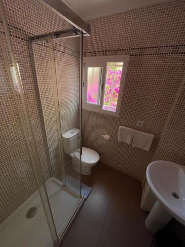 uma casa de banho com um chuveiro, um WC e um lavatório. em Hostal Roberto em Palmanova