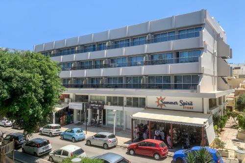 een groot gebouw met auto's geparkeerd voor het bij The Apartments by Esperia in Rhodos-stad