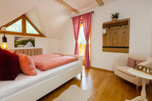 a bedroom with a bed and a chair and a window at Alpine Base Kranjska Gora in Kranjska Gora