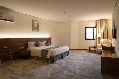 a large hotel room with a bed and a chair at Kara Hotel فندق كارا in Al Khobar