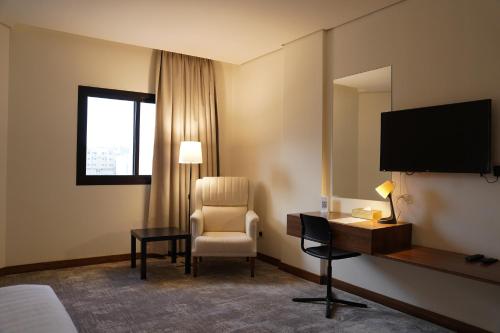 a hotel room with a chair and a desk and a television at Kara Hotel فندق كارا in Al Khobar