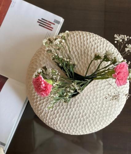 a white vase with flowers in it on a table at Hotel Ketan in Pune