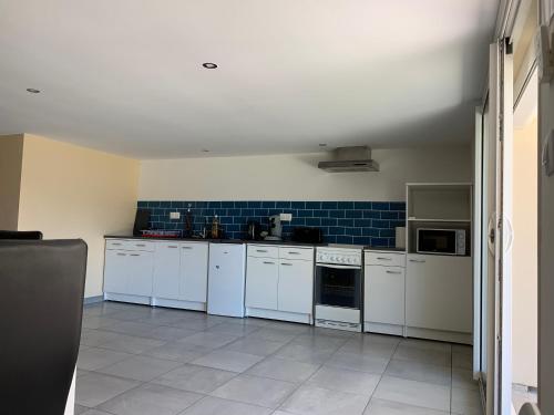 a kitchen with white appliances and blue tiles at Dépendance chaleureuse et calme in Champagneux
