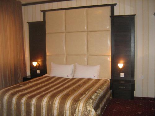 a hotel room with a large bed with two lamps at Hotel Villa Ofir in Sandanski