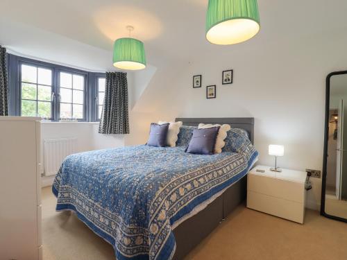 a bedroom with a bed with a blue comforter and two lamps at 9 Oaks Court in Leiston