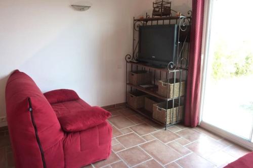 un salon avec une chaise rouge et une télévision dans l'établissement Gîte La Vigne 2 pers - uniquement samedi au samedi, à Saint-Privat