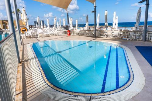 a swimming pool on a cruise ship with the ocean in the background at Beachfront Boutique Apartment in Herzliya