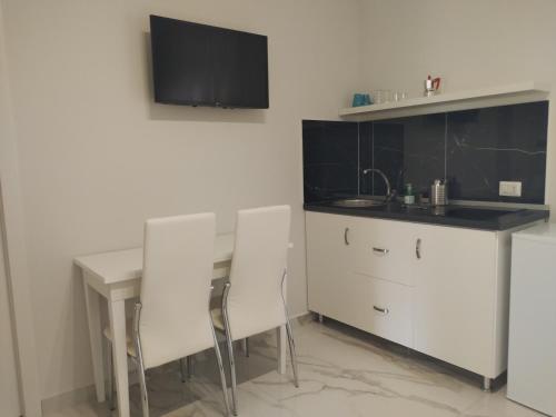 a kitchen with a table and white chairs and a sink at Villa Laura Residence Hotel Apartments & Studios in Ascea