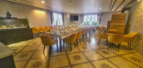 a dining room with a long table and yellow chairs at Villa Florencia in Bardejov