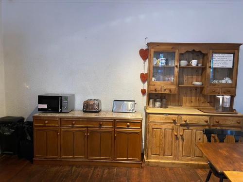 a kitchen with wooden cabinets and a microwave on a counter at THE LODGE BOURNEMOUTH in Bournemouth