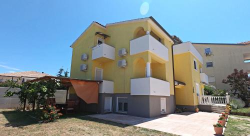 a large yellow building with white balconies on it at Villa Antonia in Medulin