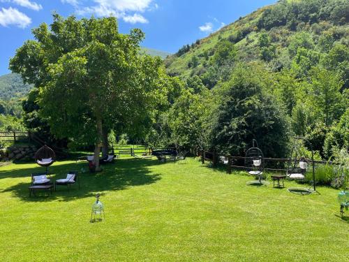 a park with chairs and a tree and mountains at Hotel Eigón in Posada de Valdeón