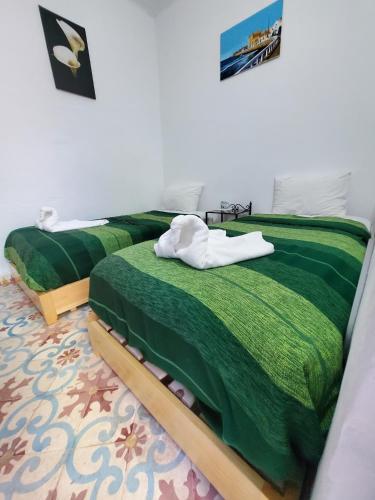 a bedroom with two beds with green comforter at Riad AYLAL in Essaouira