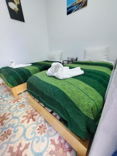 a bedroom with a bed with a green comforter at Riad AYLAL in Essaouira