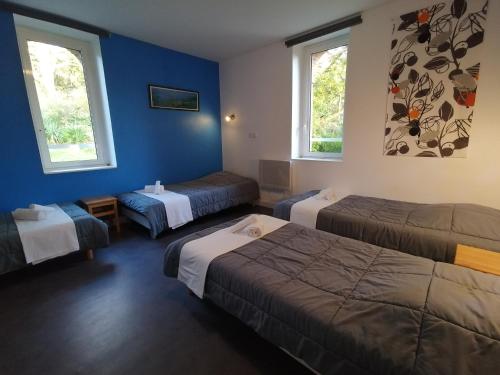 a hotel room with three beds and two windows at Village de Gîtes du Moulin Neuf in Gétigné