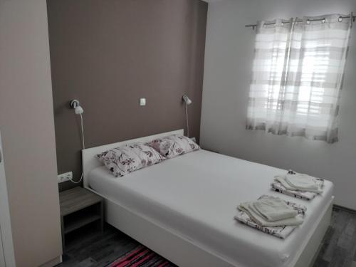 białe łóżko w pokoju z oknem w obiekcie Apartmani Verica w mieście Karlobag