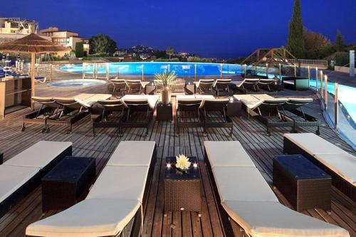 a deck with tables and chairs next to a pool at Le Hameau Cap Estérel in Valescure