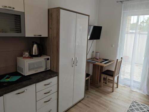 uma cozinha com um armário branco e uma secretária com um micro-ondas em MONDO - self check in em Osijek