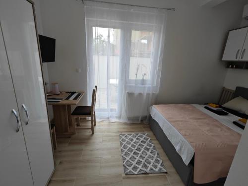 a bedroom with a bed and a desk and a window at MONDO - self check in in Osijek