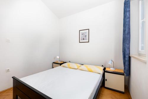 a small bedroom with a bed and a window at Apartments Mrak in Punat