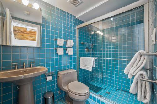 Baño de azulejos azules con aseo y lavamanos en ZEY HOTEL, en Greenport