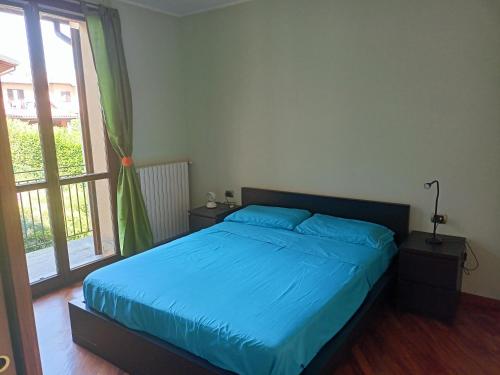 1 dormitorio con cama con sábanas azules y ventana en Tramonto al Lago, en Gavirate