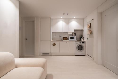 a white living room with a couch and a kitchen at Koon Terrace Stay in Seoul