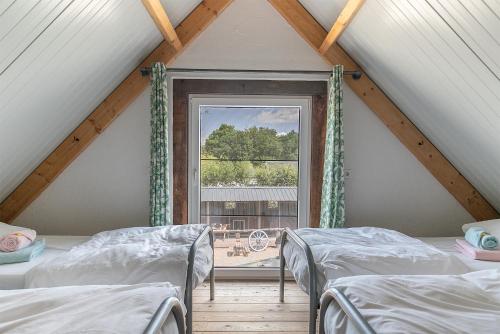 dwa łóżka w pokoju z oknem w obiekcie BoksheideBuiten w mieście Eersel