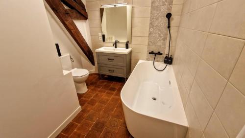 a bathroom with a tub and a toilet and a sink at La Villa 1848 by Vindihouses - piscine chauffée - sauna - billard - babyfoot in Épinac-les-Mines