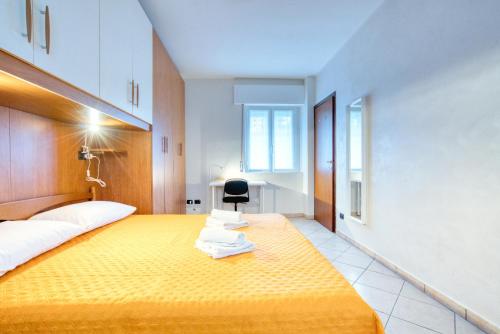 a bedroom with a large yellow bed with a black chair at CaseOspitali - Casa Valza, bilocale in contesto di corte per 4 in Cernusco sul Naviglio