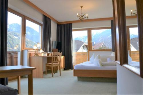 a hotel room with a bed and a desk and window at Hotel Alpina nature-wellness in Wenns