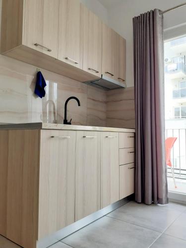 una cucina con mobili in legno, un lavandino e una finestra di Vila Manuel a Shëngjin