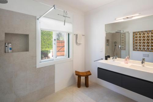 ein weißes Badezimmer mit Waschbecken und Fenster in der Unterkunft Villa Atlantico in Poço Partido