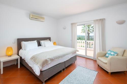 ein Schlafzimmer mit einem Bett, einem Stuhl und einem Fenster in der Unterkunft Villa Atlantico in Poço Partido