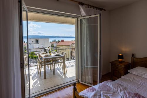 a bedroom with a bed and a balcony with a table at Apartments Lonzor in Selce