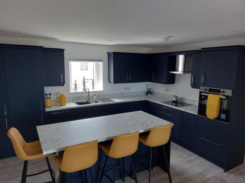 una cocina con armarios azules y una mesa con sillas en Ocean View, en Newry
