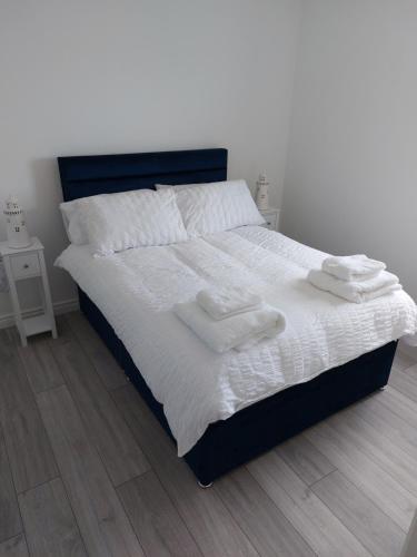 1 dormitorio con 1 cama con sábanas blancas y toallas en Ocean View, en Newry