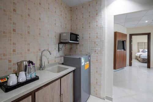 a kitchen with a sink and a refrigerator at Rose Al Medina Hotel in Al Madinah