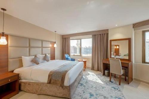 a hotel room with a large bed and a desk at Rose Al Medina Hotel in Al Madinah