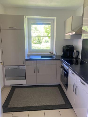 a white kitchen with a sink and a window at Ferienwohnung Heimatglück 2-3 Personen 65qm WLAN in Breitbrunn am Chiemsee