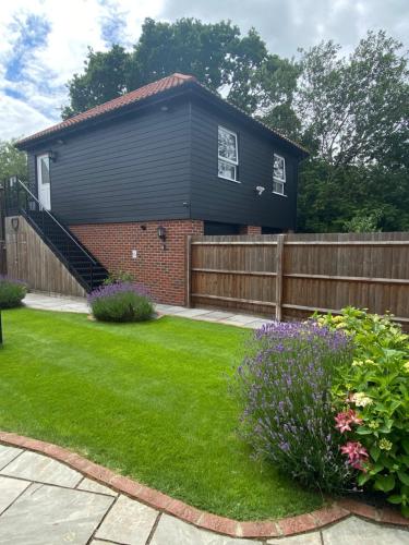 a black house with a fence and a yard at Stansted Coach House in Elsenham