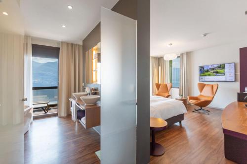 una camera d'albergo con letto e scrivania di Parkhotel Brenscino Brissago a Brissago
