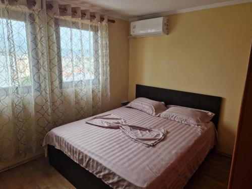 een slaapkamer met een bed met witte lakens en een raam bij Stella del Lago Family Apartment Deluxe Penthouse in Pogradec