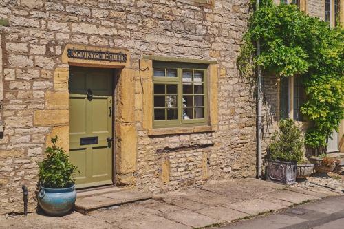 a stone building with a green door and a window at Coniston House in Stow on the Wold