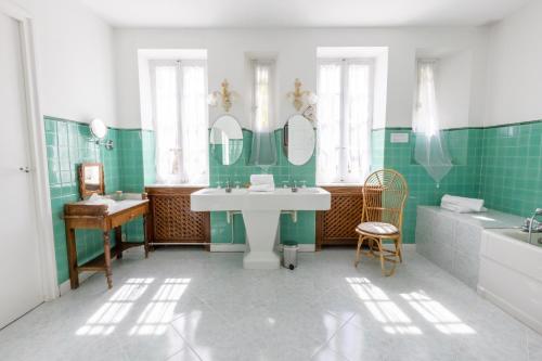 La salle de bains est pourvue de carrelage vert, d'un lavabo et d'une baignoire. dans l'établissement Château de Floure - SPA et piscine extérieure chauffée, à Carcassonne