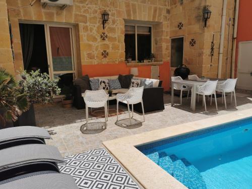 un patio con piscina, sillas y sofá en Large Bedroom in Boutique Style Farmhouse B&B with Pool, en Il-Pergla
