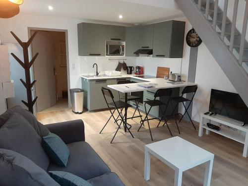 ein Wohnzimmer mit einem Sofa und einem Tisch sowie eine Küche in der Unterkunft Appart Cocooning in Périgny