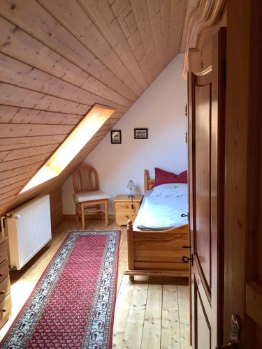 a bedroom with a bed and a rug in a attic at HAusZeit Kaptitänshaus Friedrichsschleuse in Carolinensiel